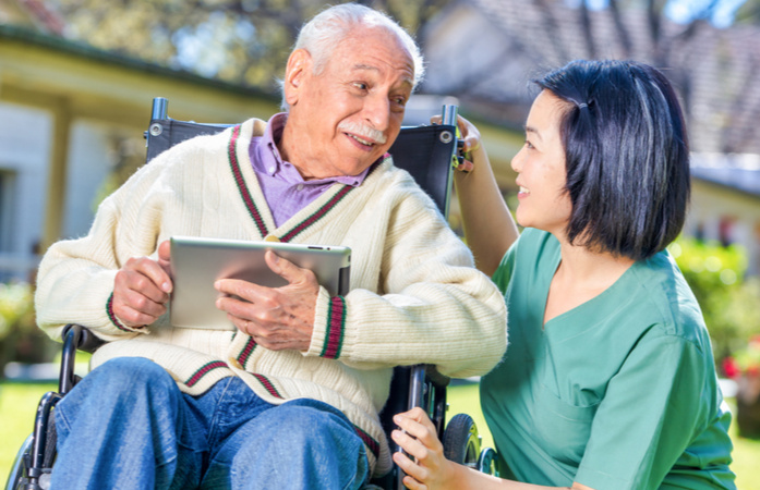 Personne âgée en chaise roulante avec une tablette.